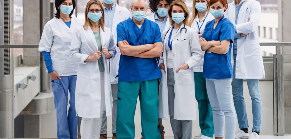 A group of doctors with face masks looking at camera, corona virus concept.